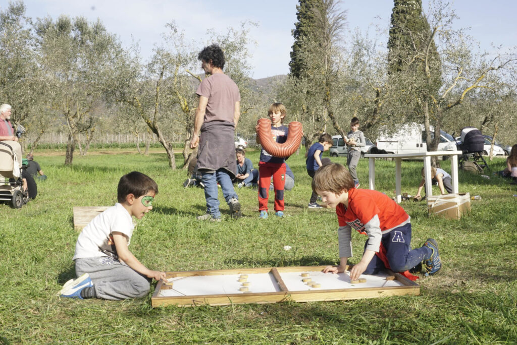 bambini e grandi che giocano nei terreni di Mondeggi con giocattoli autocostruiti